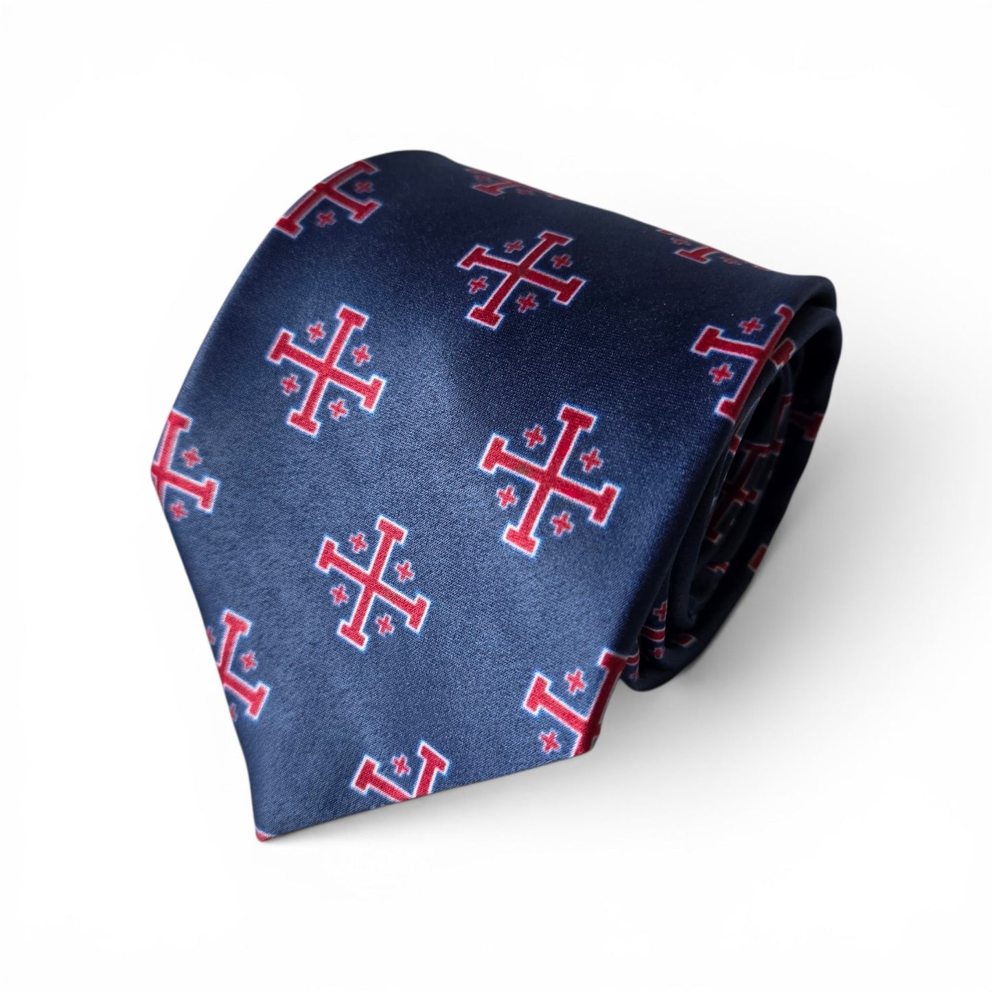 American Jerusalem Cross necktie in navy blue with repeating red and white Jerusalem Cross pattern, rolled product shot on white background