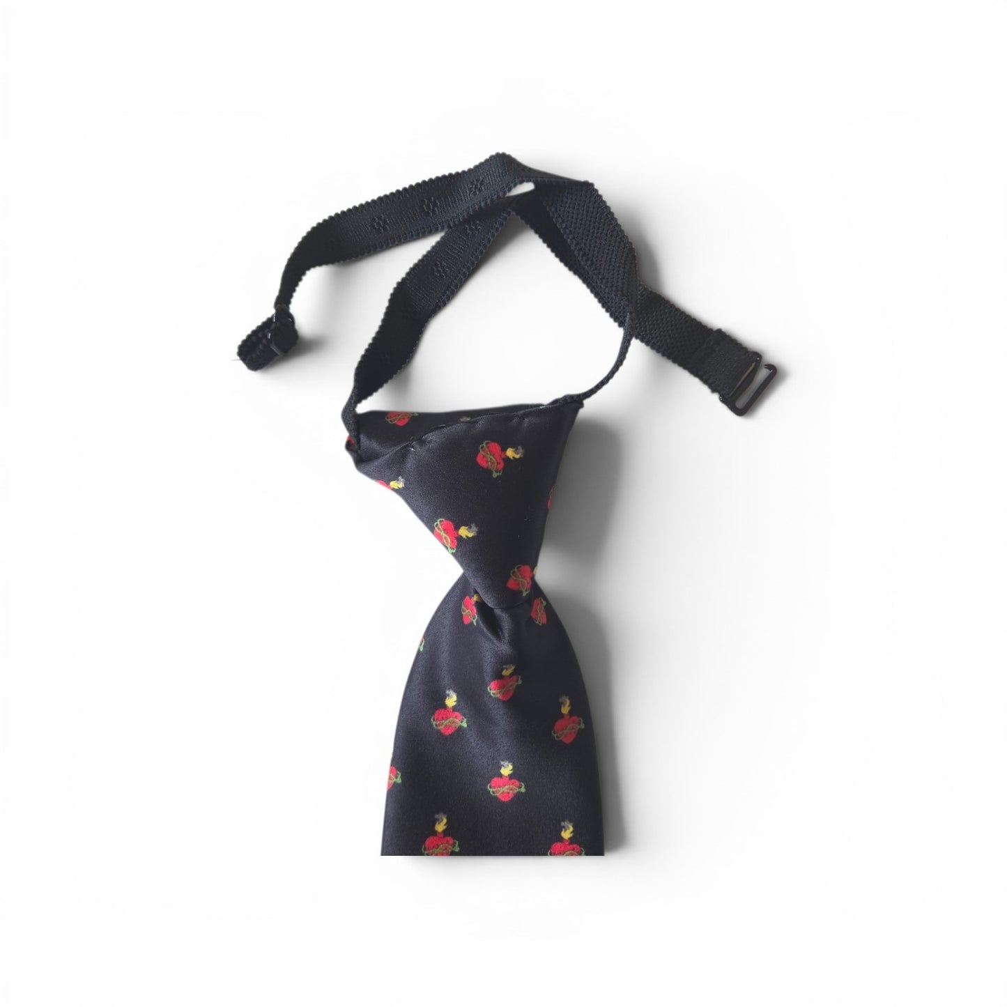 Boys Sacred Heart of Jesus pretied necktie in navy blue with repeating red Sacred Heart pattern, showing adjustable neck strap and buckle closure on white background