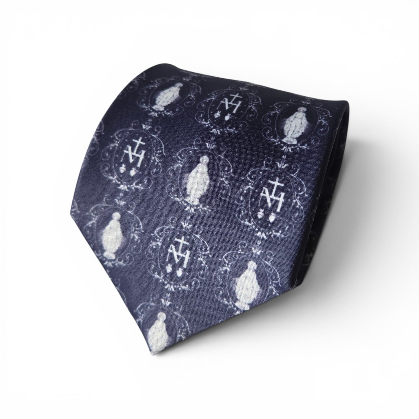 Miraculous Medal necktie in navy blue with repeating white Our Lady and Marian monogram medallion pattern, rolled product shot on white background