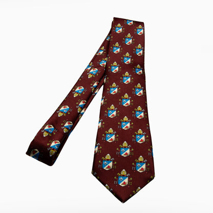 Pope Leo XIV maroon necktie featuring papal coat of arms heraldic pattern, full length flat lay on black background